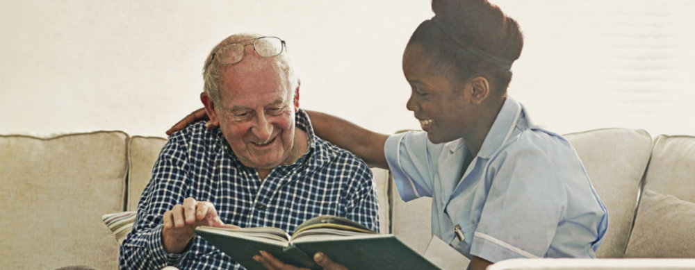 a caregiver reading a book with her elderly patient